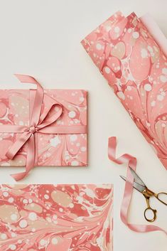 the wrapping paper is pink with white swirls on it and has a ribbon tied around it