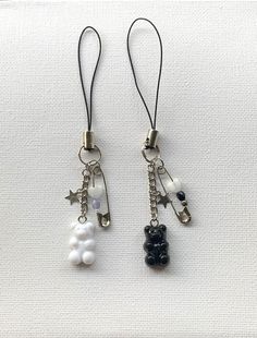 two key chains with charms attached to them on a white surface, one is black and the other is white