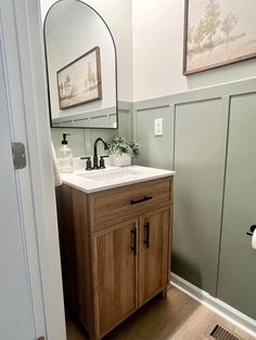 a bathroom with a sink, mirror and toilet paper dispenser in it