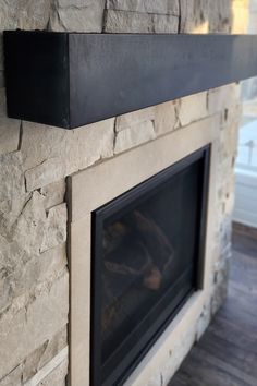 a stone fireplace with a black mantle above it