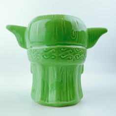 a green ceramic vase with an intricate design on it