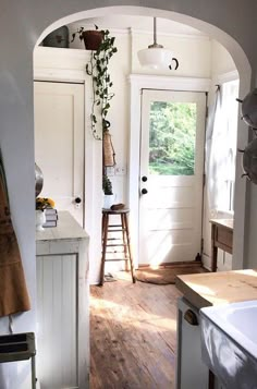 an archway leading to a kitchen with a sink and counter top next to a window