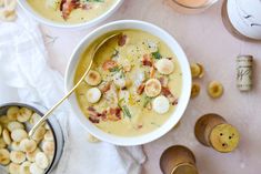 two bowls filled with soup next to some bread and crackers on a table top