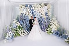 a bride and groom standing in front of a floral backdrop with the word asta on it