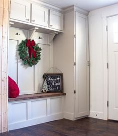 a christmas wreath is hanging on the wall next to a bench with a chalkboard