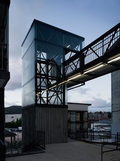 a tall building sitting next to a bridge on top of a cement floor covered ground