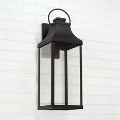 a black lantern hanging on the side of a white brick wall