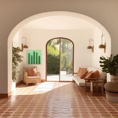 an archway leading to a living room with couches and potted plants