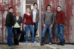 a group of people standing next to each other in front of a red barn door