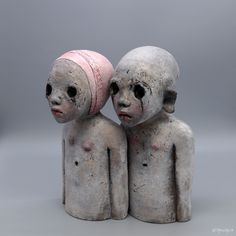 two ceramic figurines that look like they are holding each other's head