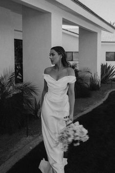 a black and white photo of a woman in a wedding dress walking down the street