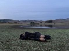 a person laying on the ground next to a lake