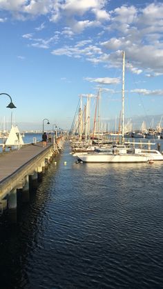 several boats are docked at the pier on a sunny day with blue skies and white clouds