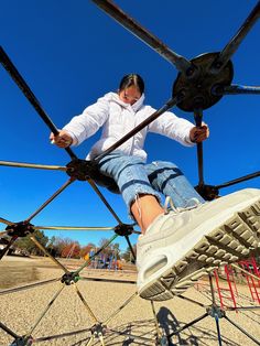 a woman in white shirt and jeans standing on top of a metal structure with wheels