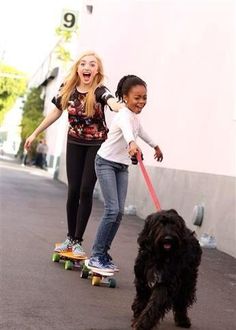 two girls skateboarding with a dog on a leash