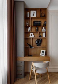 a wooden desk sitting under a window next to a book shelf