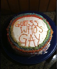 a birthday cake with the words guess who's gay on it sitting on a blue plate