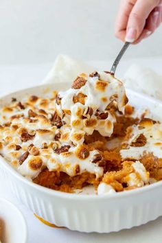 a person scooping some kind of dessert out of a white casserole dish