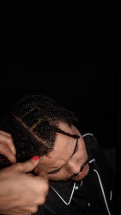 a man with dreadlocks is getting his hair done by another person in the dark