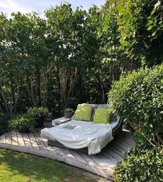 a bed sitting on top of a wooden platform in the middle of a lush green field