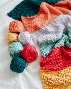 crocheted blankets and balls of yarn laid out on a bed