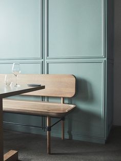 a wooden bench sitting in front of a table with wine glasses on top of it