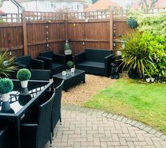 an outdoor patio with black furniture and potted plants