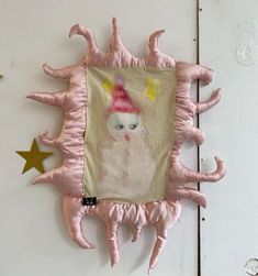 a pink stuffed animal hanging on the side of a white wall with stars around it