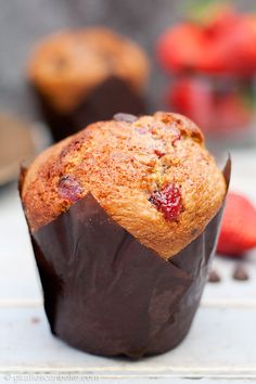 a chocolate muffin with strawberries in the background