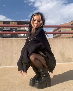 a woman in black boots is posing for the camera with her leg up on a skateboard