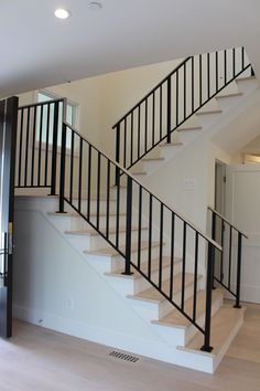 an empty room with stairs and hard wood flooring