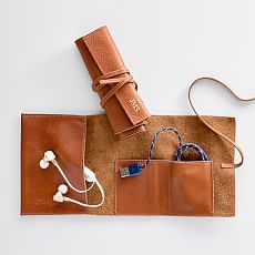 a brown case with earbuds and headphones in it on a white surface