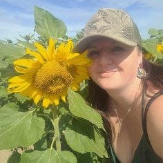 a woman standing in front of a sunflower with her face close to the camera