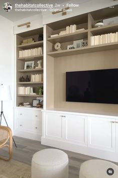 there is a television on the wall in this living room with white furniture and bookshelves