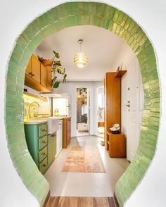 an oval view of a kitchen with green tiles on the wall and wood flooring