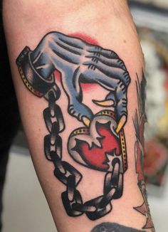 a man with a tattoo on his arm holding a chain and heart in the shape of a panther