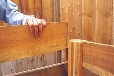 a person holding their hand on the back of a wooden bench