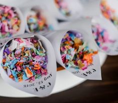 several spoons filled with colorful confetti on top of a white plate