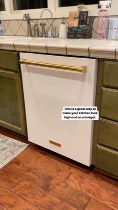 a white dishwasher sitting on top of a wooden floor next to a kitchen counter