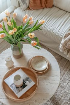 a coffee table with flowers in a vase and plates on the table next to it