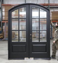 a man standing in front of a black double door with glass panels on the side