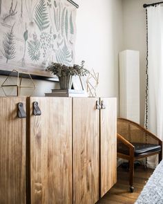 a room with a wooden cabinet next to a window and a painting on the wall