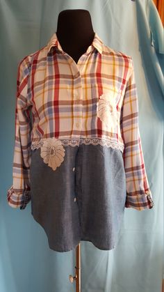 a plaid shirt with patches and lace on the front is hanging on a mannequin's dummy