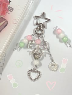 a close up of a cell phone charm on a white surface with pink and green beads