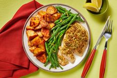 a white plate topped with meat and green beans next to a red napkin on top of a table