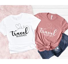 two t - shirts with the words travel buddies and hearts on them, sitting next to each other