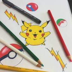 some pencils and markers are laying on top of a sheet of paper with pokemon drawings