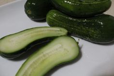 three cucumbers are sitting on a white plate