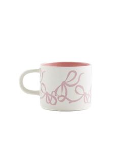 a white and pink coffee cup with flowers on it's rim, against a white background