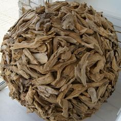 a large ball made out of driftwood sitting on top of a white table next to a window